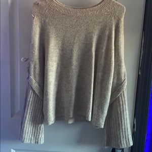 A creamed color sweater with flared out sleeves